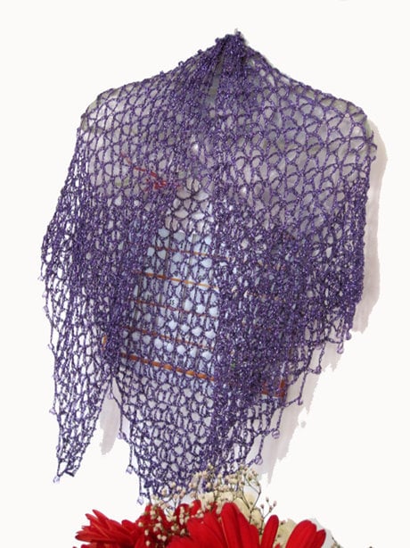 Eggplant purple lurex shawl hanging in a soft drape, side view with red flowers arranged below.